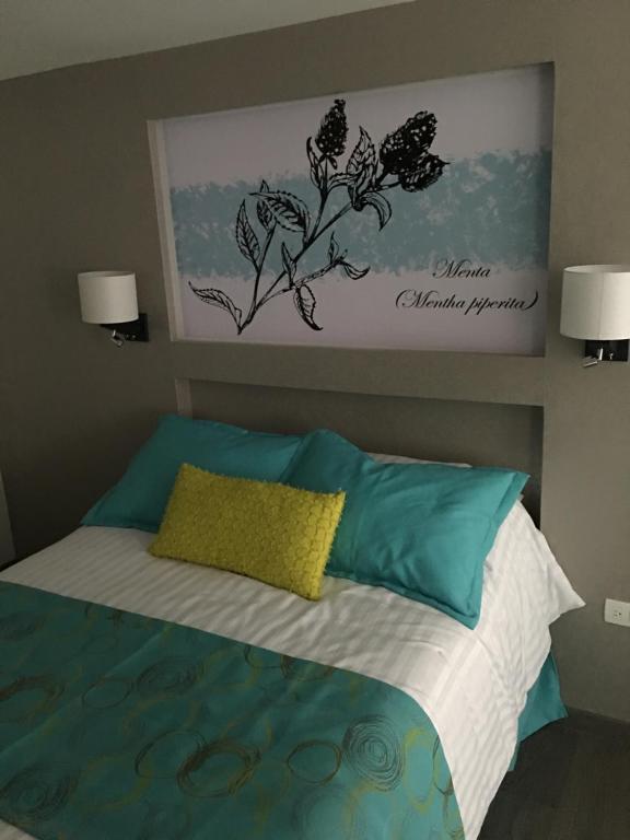 Herbal Inn Suites في بوبلا: غرفة نوم مع سرير ووسائد زرقاء وأخضر