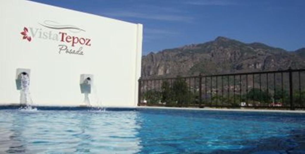 een gebouw met een zwembad met bergen op de achtergrond bij Posada Vista Tepoz in Tepoztlán