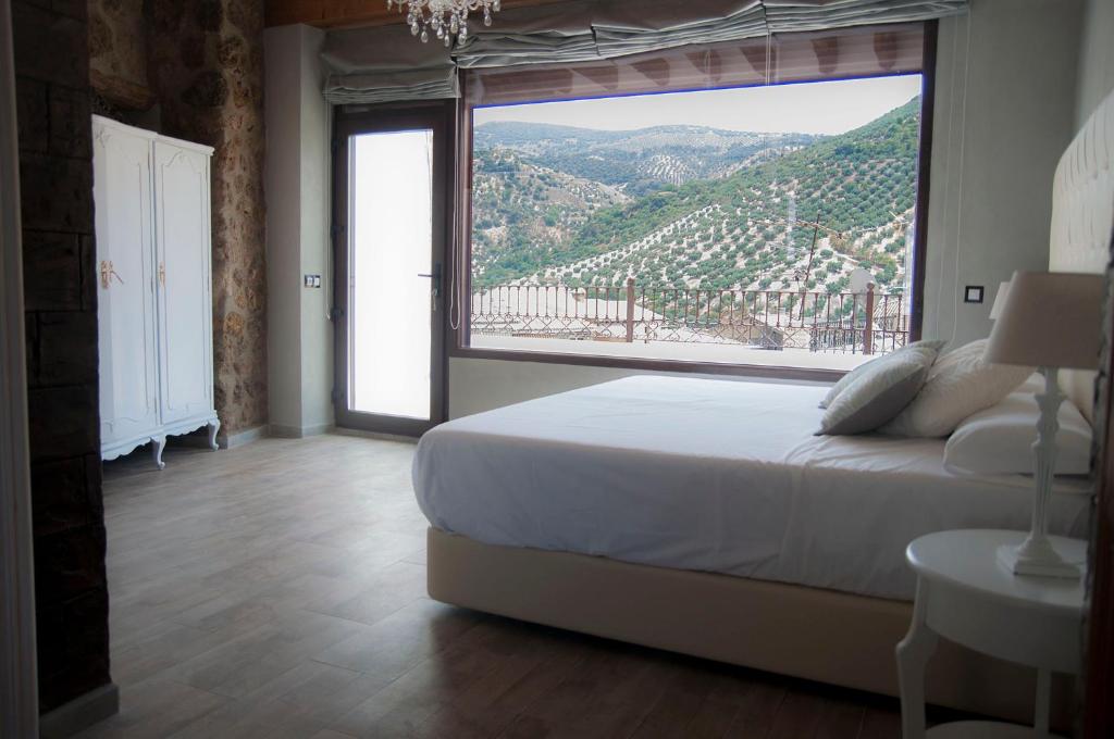 a bedroom with a large bed and a large window at La Casa De Maria in Algarinejo