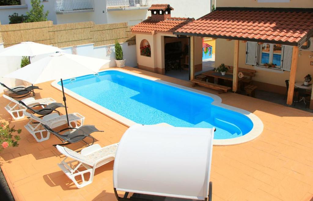 a swimming pool with chairs and a house at Apartment Darija with private pool in Kaštela