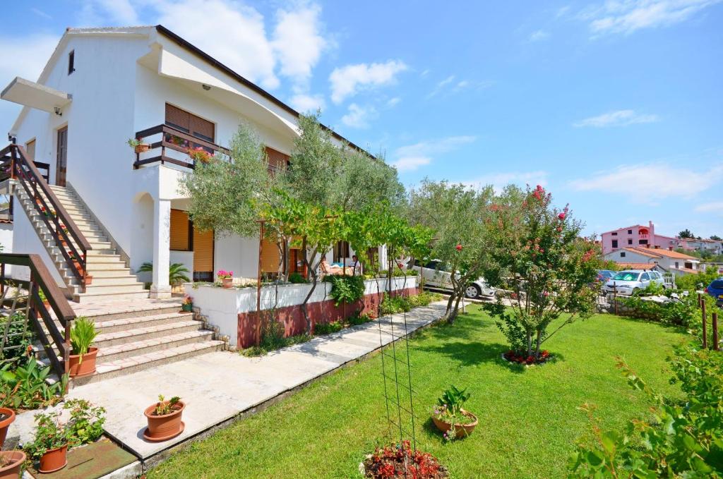 een wit huis met een tuin met planten bij Apartments Ivanka in Krk
