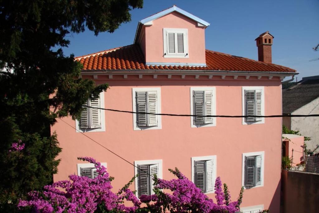 a pink house with pink flowers in front of it at Apartments Ivan in Mali Lošinj
