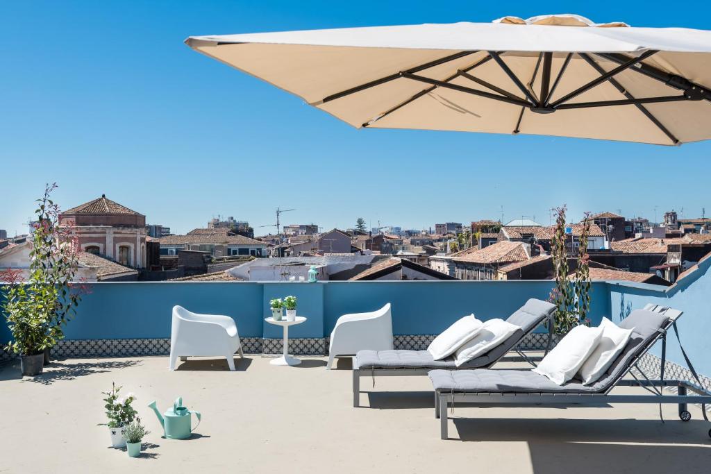 eine Terrasse mit weißen Stühlen und einem Sonnenschirm in der Unterkunft Duomo Housing Catania in Catania