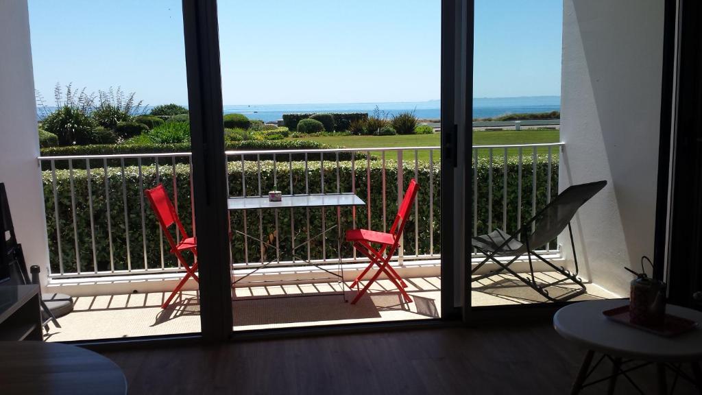 2 sedie rosse e un tavolo sul balcone di Appartement Belles Vacances a Quiberon