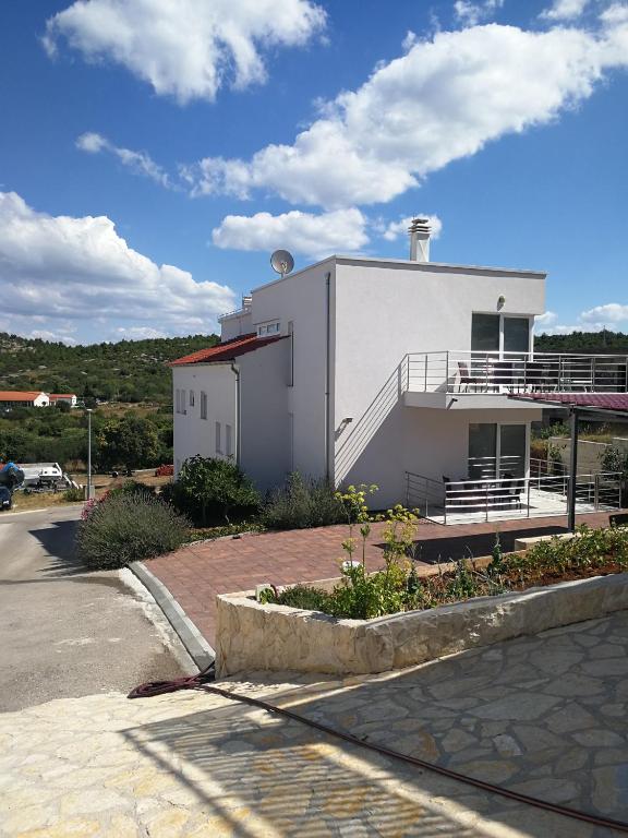 a white building with a balcony on the side of it at Apartments Bilanovic in Tisno