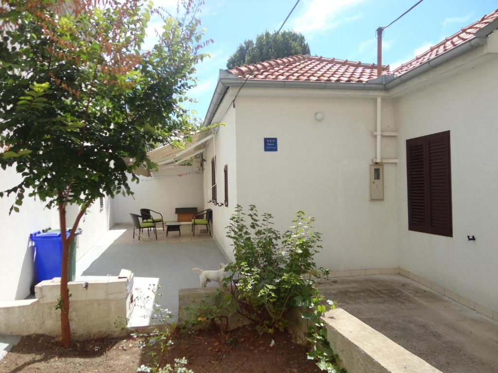 a white house with a dog sitting in the yard at Apartment Ivana in Biograd na Moru