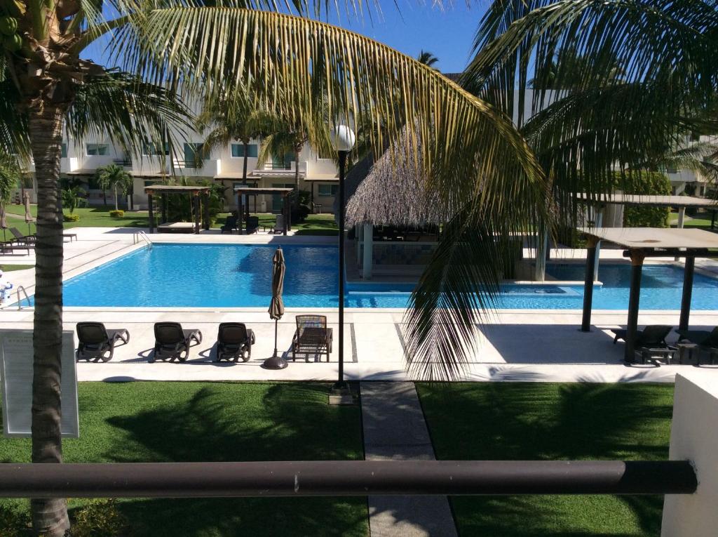 einen Pool mit Stühlen, einem Tisch und einer Palme in der Unterkunft Villa Perfecta Zona Diamante in Acapulco