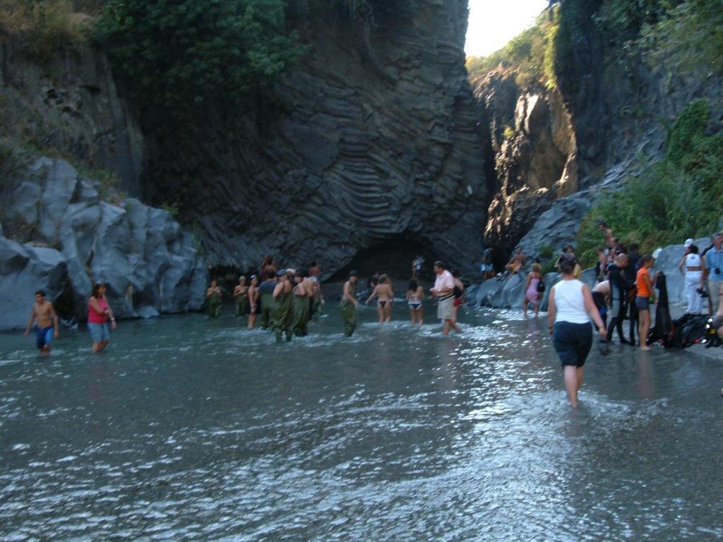 a group of people walking in the water on a beach at Gole Dell'Alcantara Villa Lucia in Motta Camastra