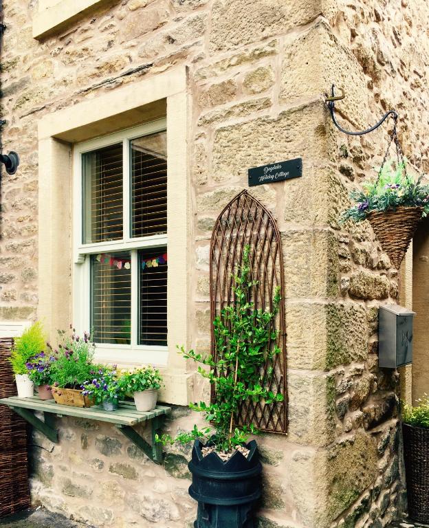 a stone building with a window and some potted plants at Dugdales Cottage in Settle