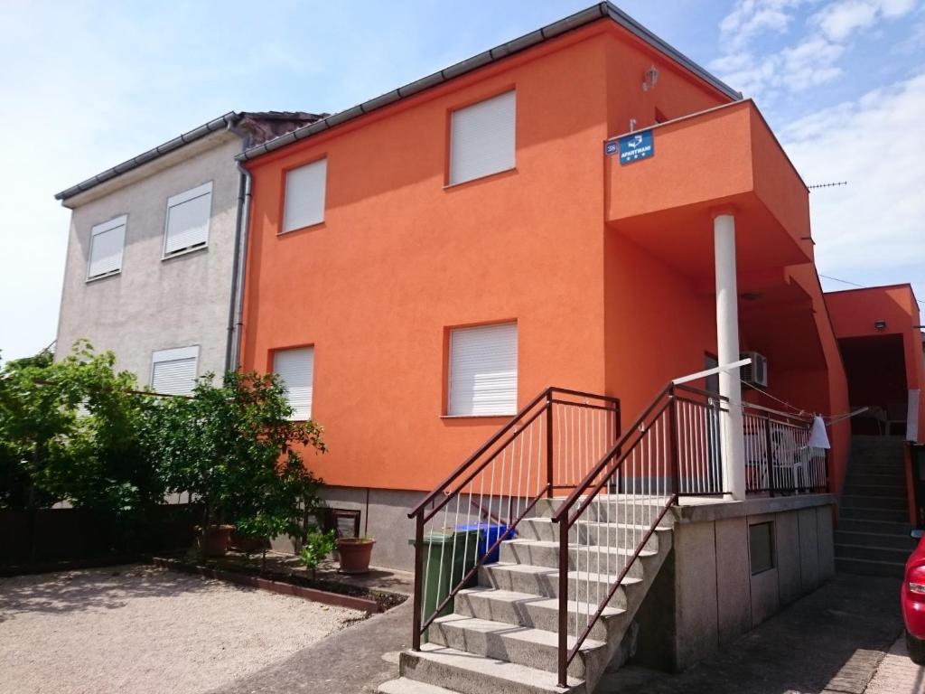ein orangefarbenes Gebäude mit einer Treppe davor in der Unterkunft Apartmani Bartolić in Biograd na Moru