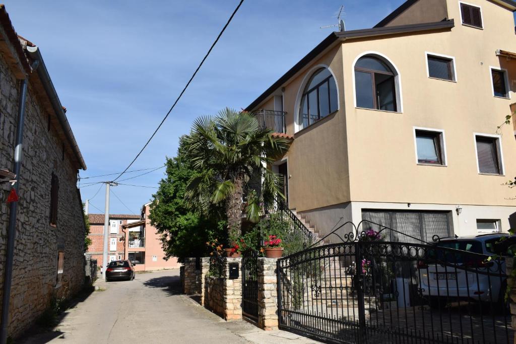 a house with a fence and a palm tree on a street at Studio apartman Mia in Tar