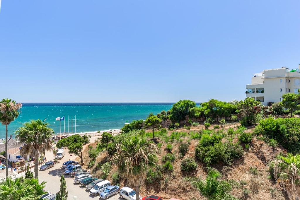 een uitzicht op een strand met palmbomen en een parkeerplaats bij Marbellamar apartamento in Mijas