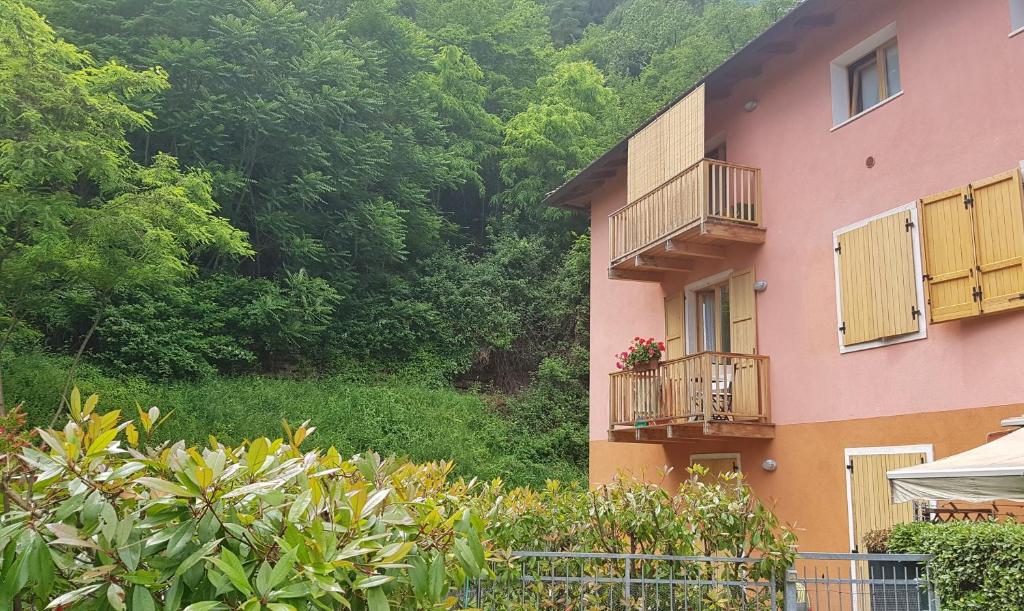 różowy budynek z balkonem z kwiatami w obiekcie Appartamento Angi - lago & vacanza attiva w mieście Riva del Garda