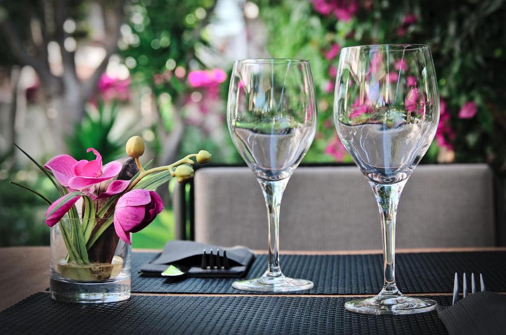 two wine glasses and a vase of flowers on a table at Hotel Boutique Ses Pitreras in San Antonio Bay