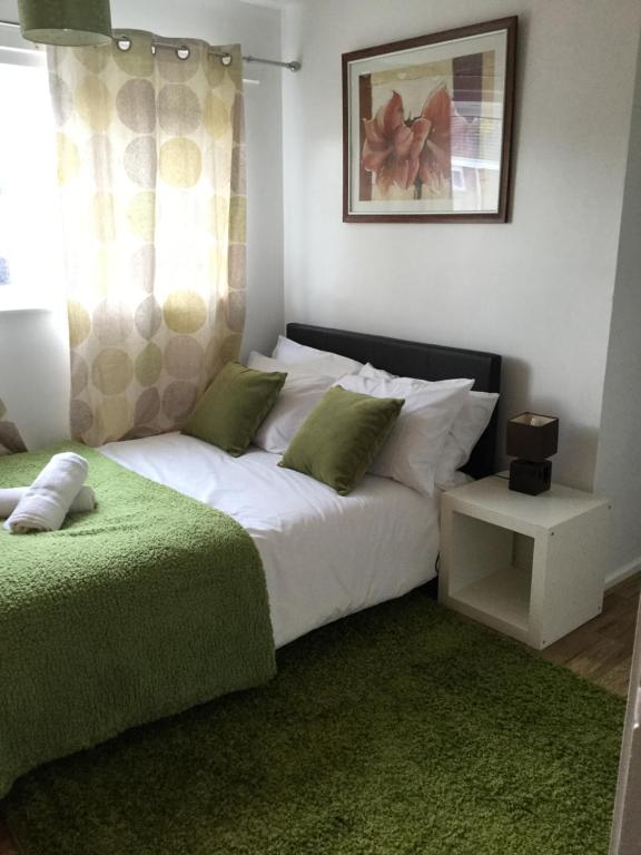 een slaapkamer met een groot wit bed met groene kussens bij 4 Bed House next to Basildon Town Centre in Basildon