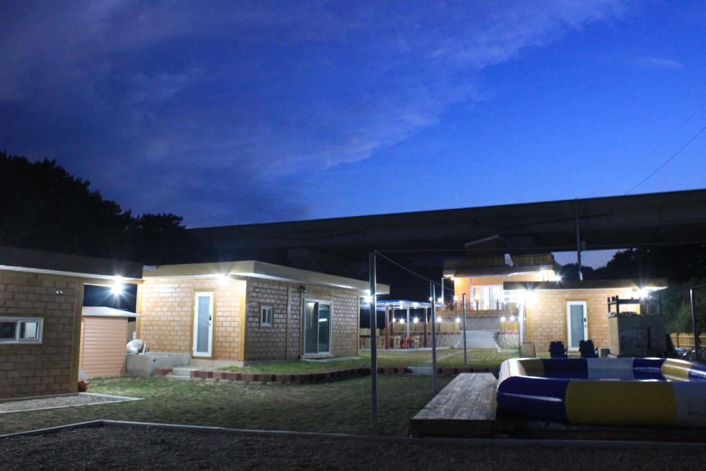 una casa con una piscina delante de ella por la noche en Tobang Red Clay Pension, en Pohang