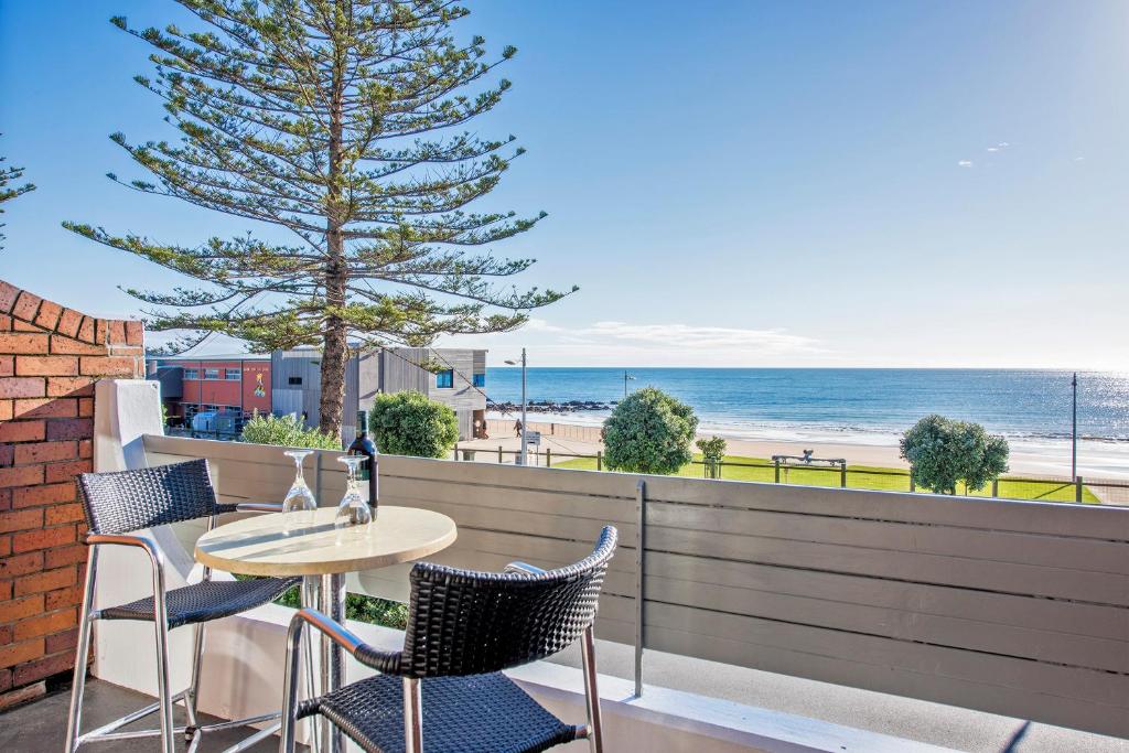 un patio con mesa y sillas y la playa en Beachfront Voyager Motor Inn, en Burnie