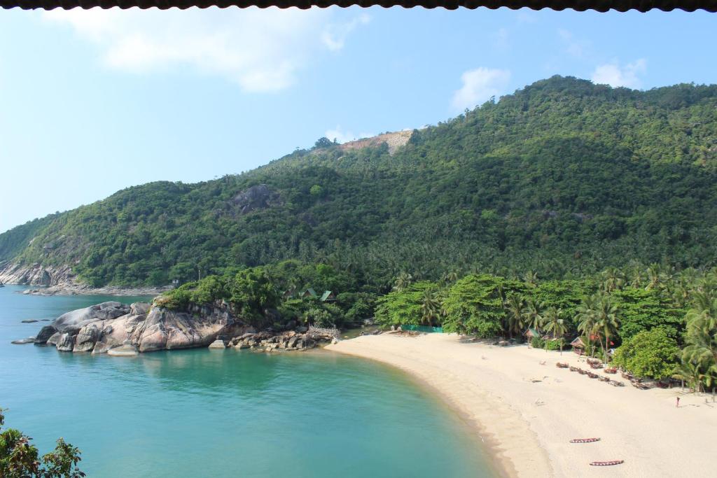 a beach with palm trees and a mountain at Plaa's Thansadet Resort in Than Sadet Beach