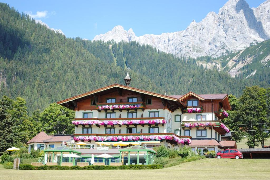 un edificio con flores delante de una montaña en Hotel Jagdhof, en Ramsau am Dachstein