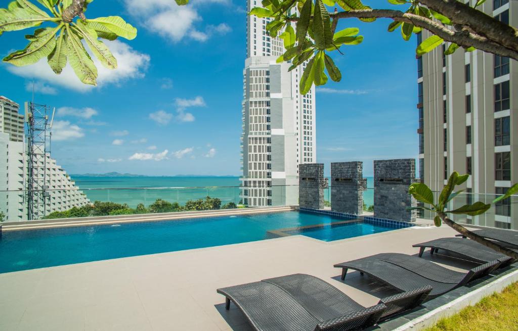 a swimming pool on the roof of a building with chairs at Serenity Condo Wongamat by Patsamon in Pattaya North
