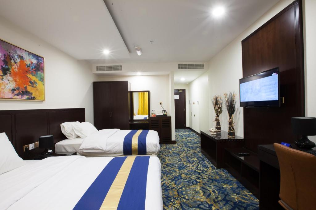 a hotel room with two beds and a flat screen tv at Amarah Hotel in Muscat