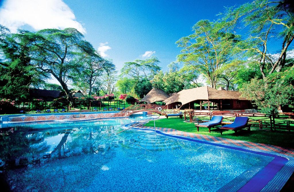 ein Pool mit blauen Stühlen und ein Haus in der Unterkunft Lake Naivasha Sopa Resort in Naivasha