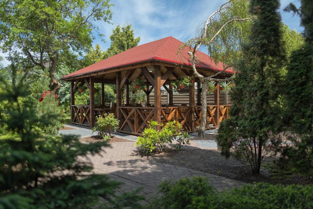 a wooden pavilion with a red roof in a park at Pensjonat Tadeusz i Apartamenty w Darłówku in Darlowko