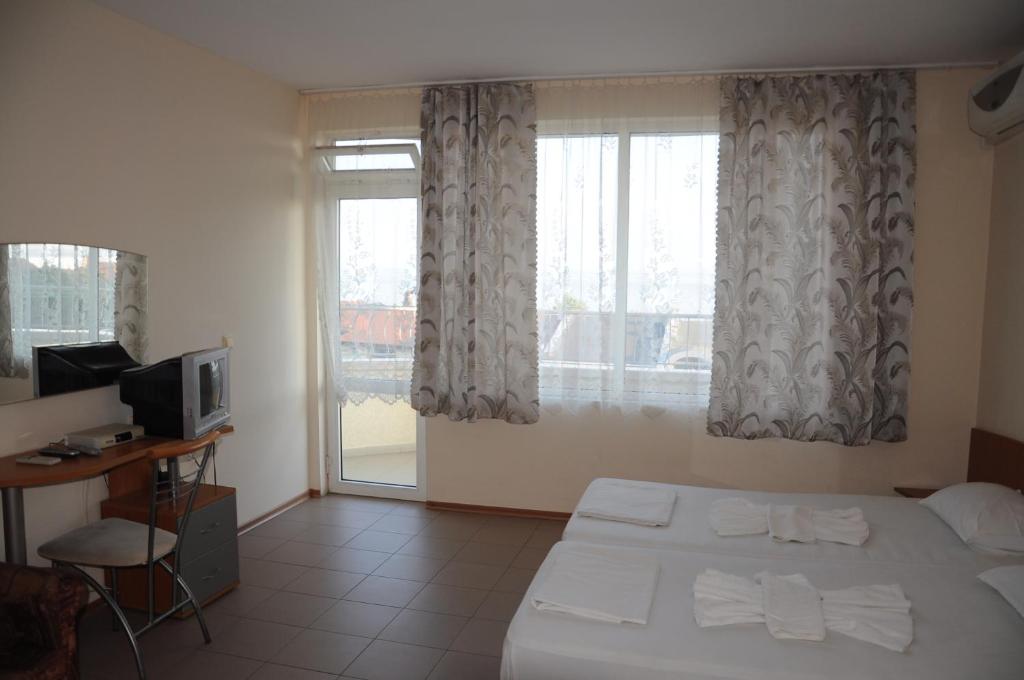a bedroom with a bed and a television and a window at Hotel Babeva in Sveti Vlas