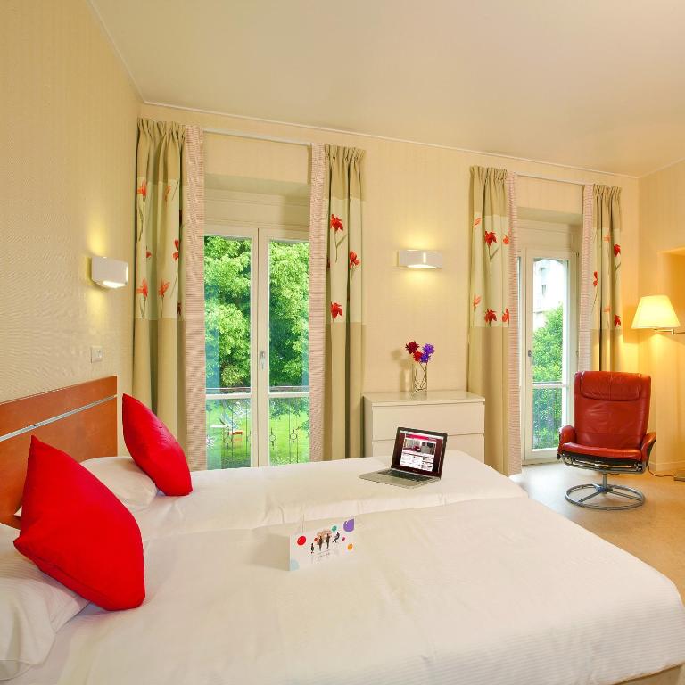 a bedroom with a large bed with a laptop on it at Hotels &amp; Résidences - Les Thermes in Luxeuil-les-Bains