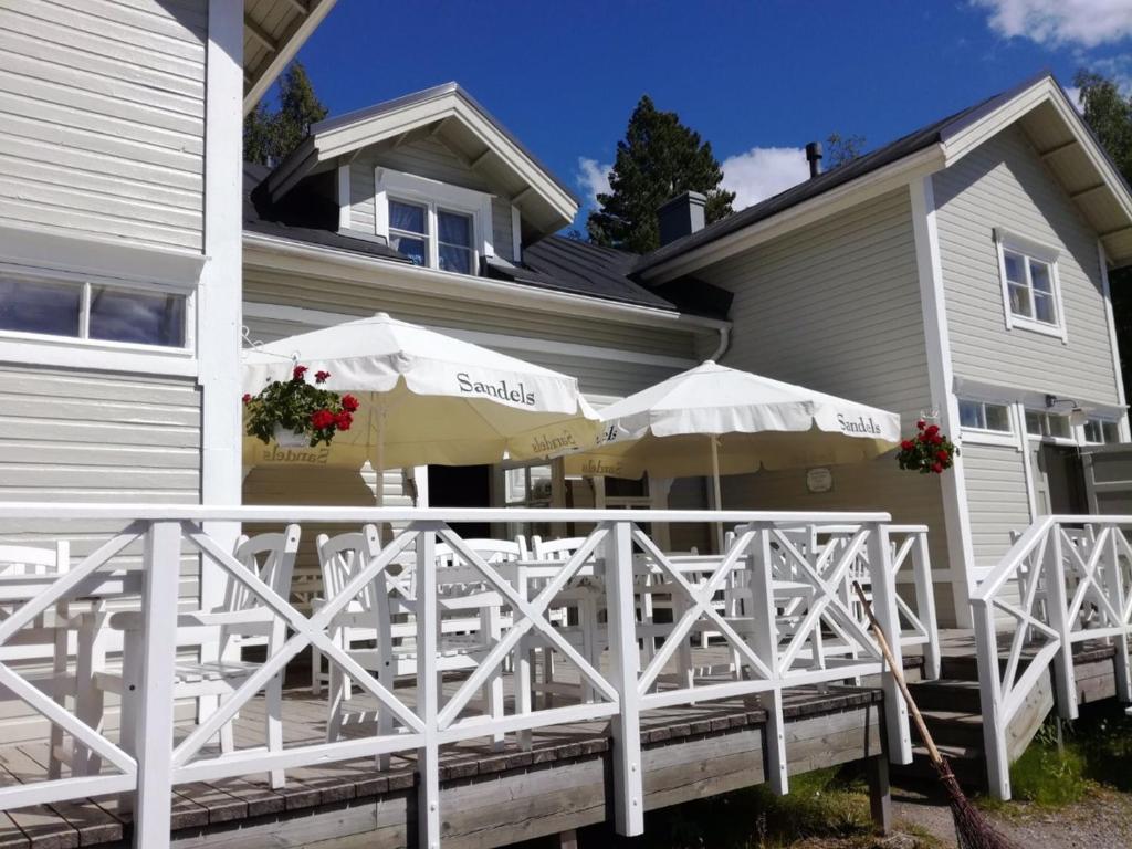 a white deck with umbrellas in front of a house at Koljonvirran Kartano in Iisalmi