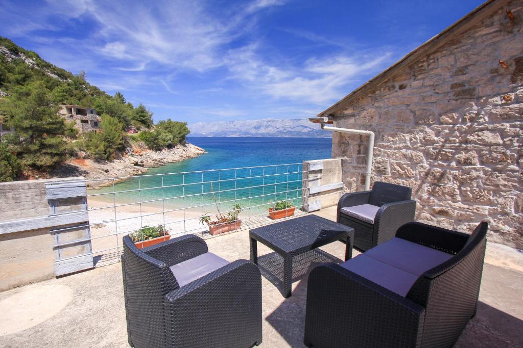 a patio with chairs and tables and a view of the water at Robinson Braco in Bogomolje