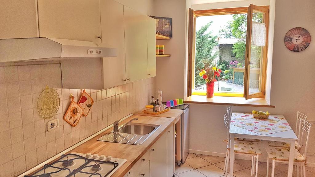 kuchnia ze zlewem, stołem i oknem w obiekcie Appartamento Angi - lago & vacanza attiva w mieście Riva del Garda