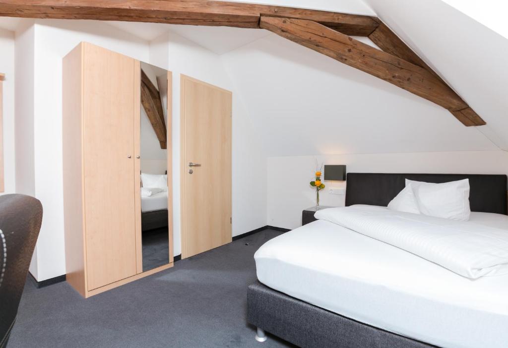 a bedroom with a white bed and a wooden ceiling at Hotel Krone in Monheim