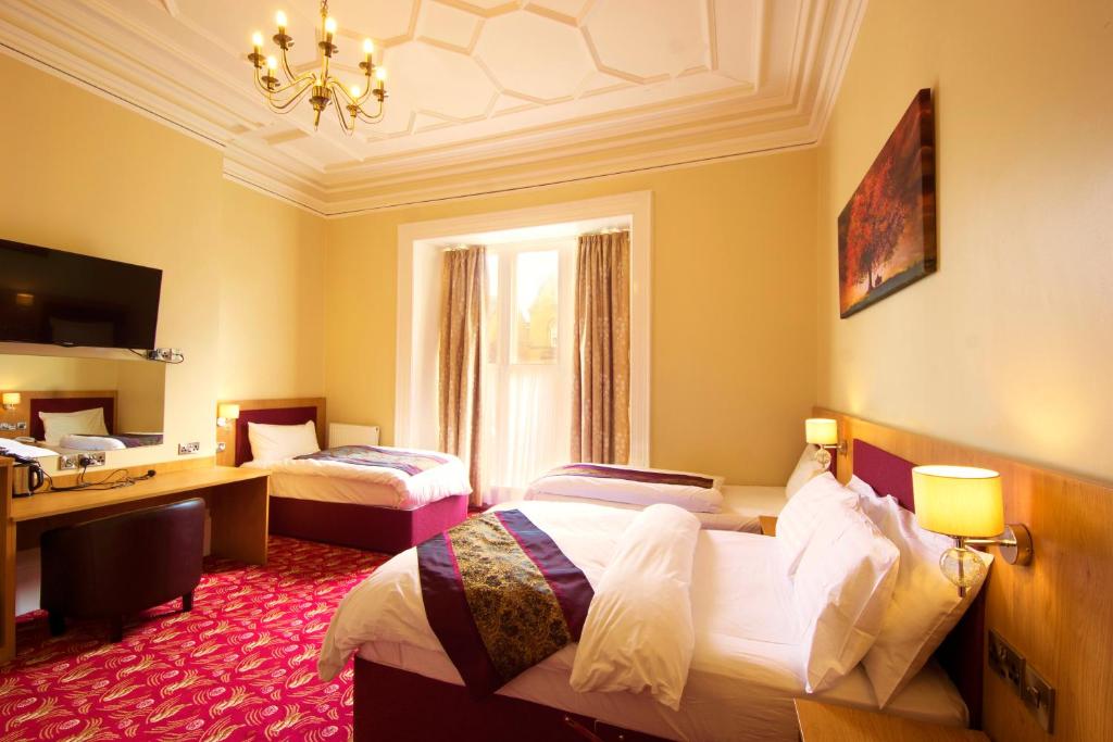 a hotel room with two beds and a desk at Edgerton Hotel in Huddersfield