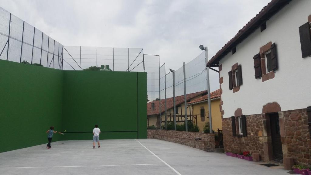 twee mensen die tennissen op een grote groene muur bij Casa Barazabal in Gorostapolo de Errazu