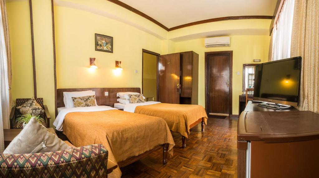 a hotel room with two beds and a flat screen tv at Hotel Excelsior in Kathmandu