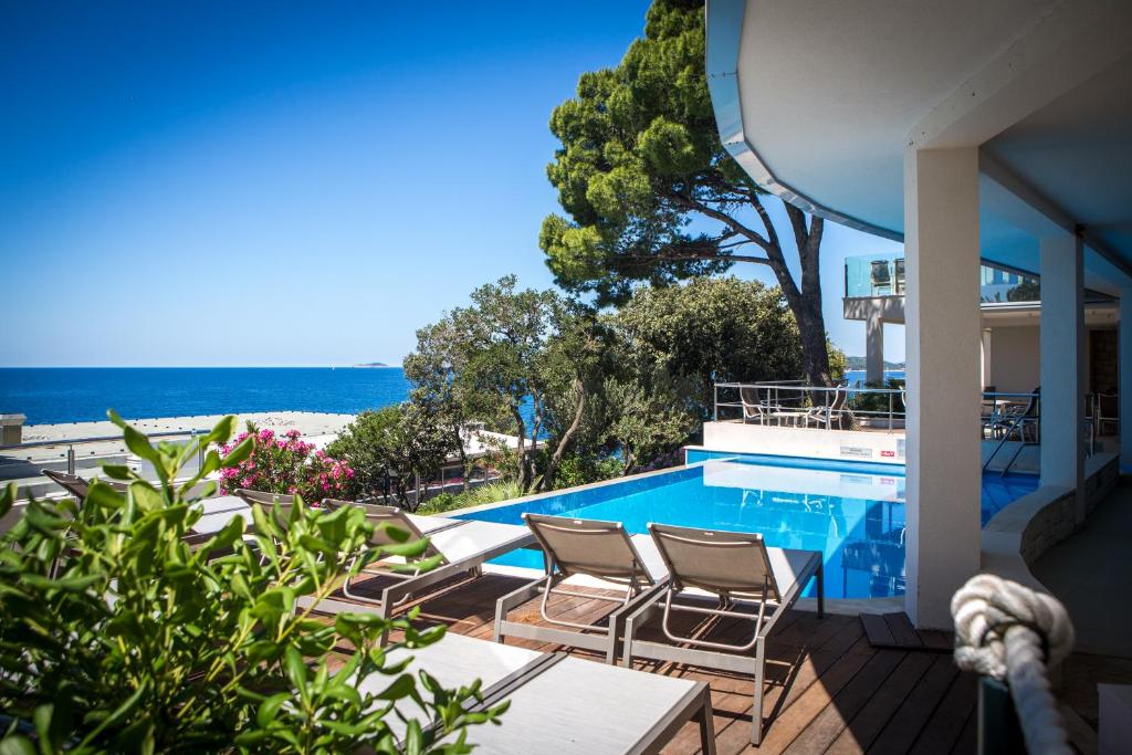 a swimming pool with chairs and a view of the beach at Royal Neptun Hotel in Dubrovnik