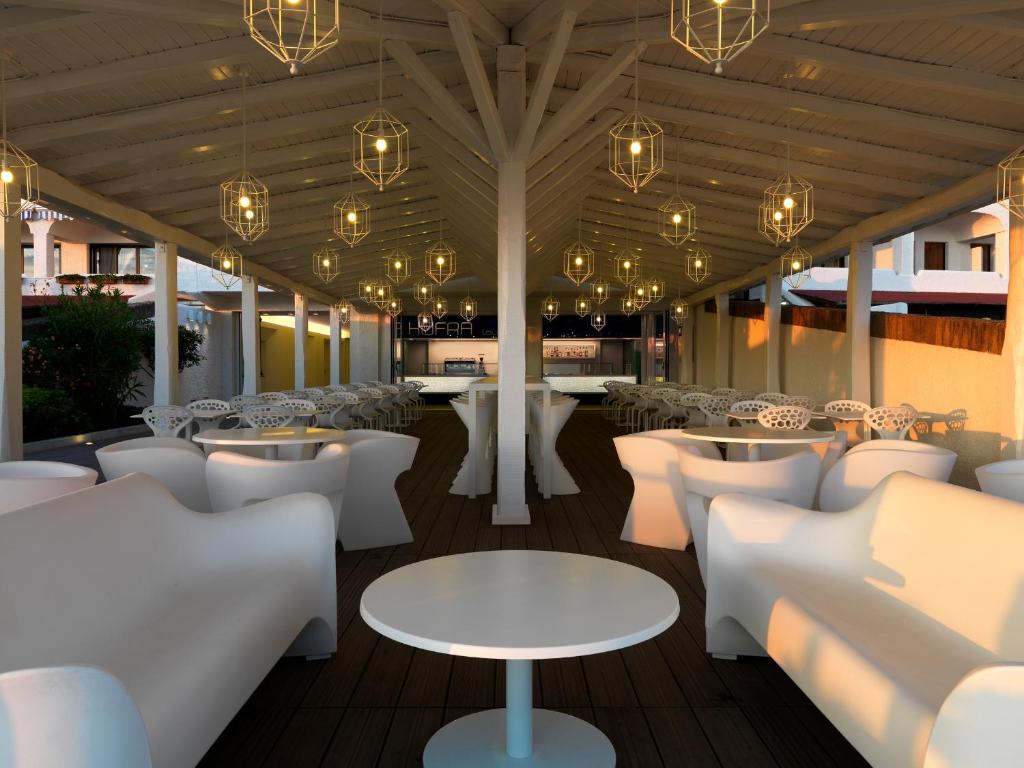 a restaurant with white chairs and tables and chandeliers at Hotel Oasi Di Kufra in Sabaudia
