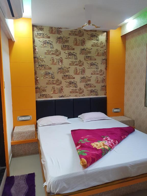 a bedroom with a large white bed with a pink blanket at Hotel Laabh in Diu