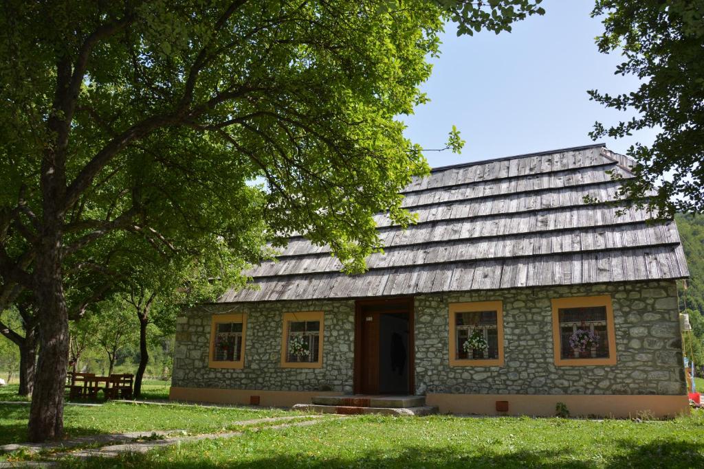 una casa de piedra con un árbol delante en Peraj Guesthouse en Vermosh