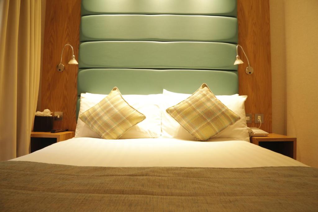a bedroom with a bed with a blue headboard and pillows at Astors Belgravia in London