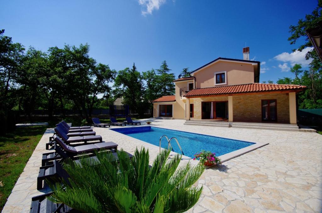 a swimming pool with chairs and a house at Vila Foška in Žminj