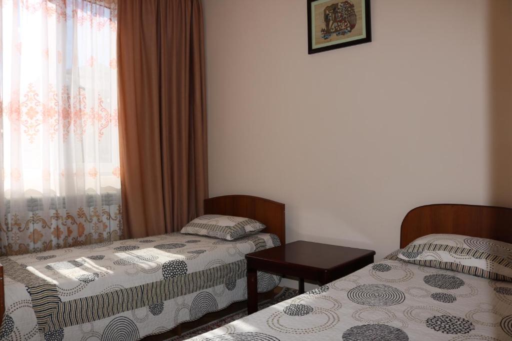 a room with two beds and a table and a window at Гостевой дом "Kalinka" in Cholpon-Ata