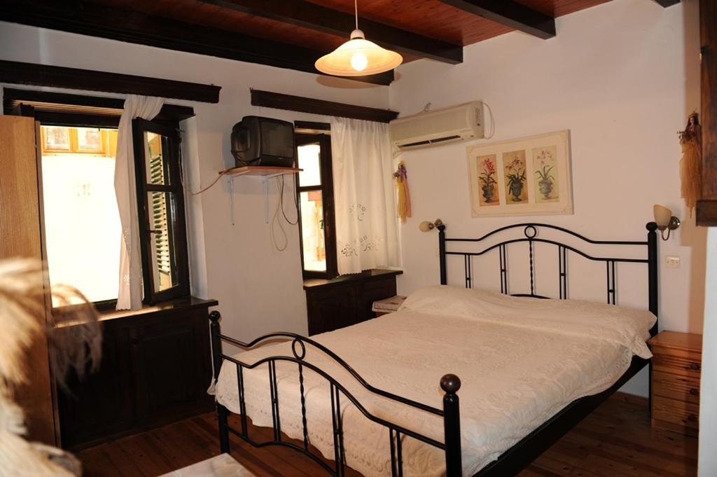 a bedroom with a bed and a tv and windows at Eleonora in Chania Town
