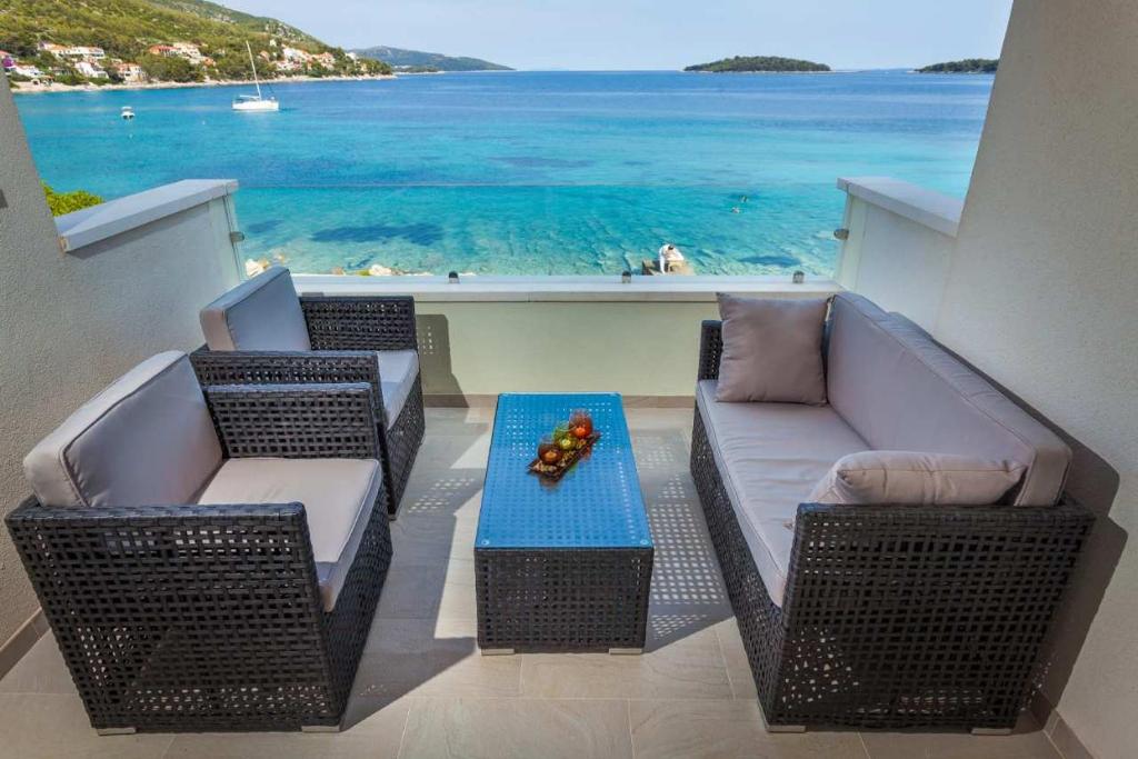 Un balcón con 2 sillas y una mesa con vistas al océano. en Žal Beach Apartments, en Prizba