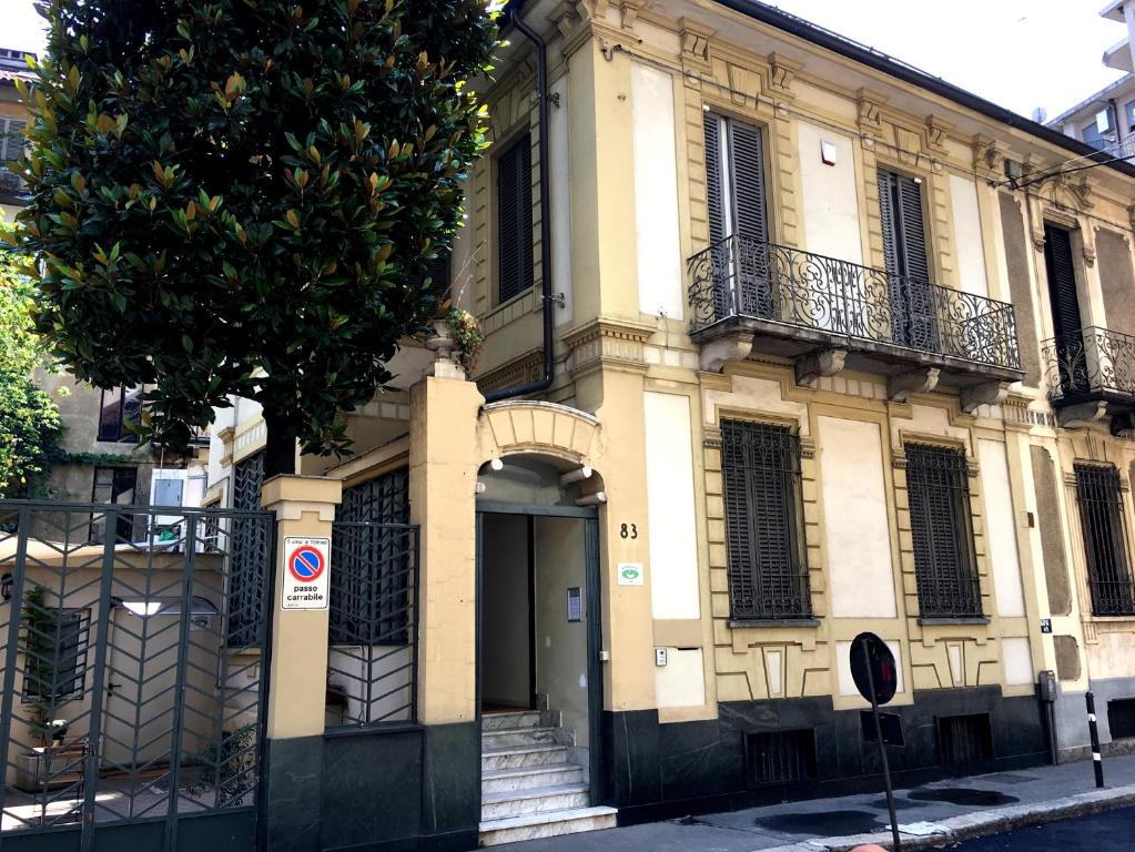 un bâtiment avec une porte et un arbre en face de celui-ci dans l'établissement Gabriele 83, à Turin