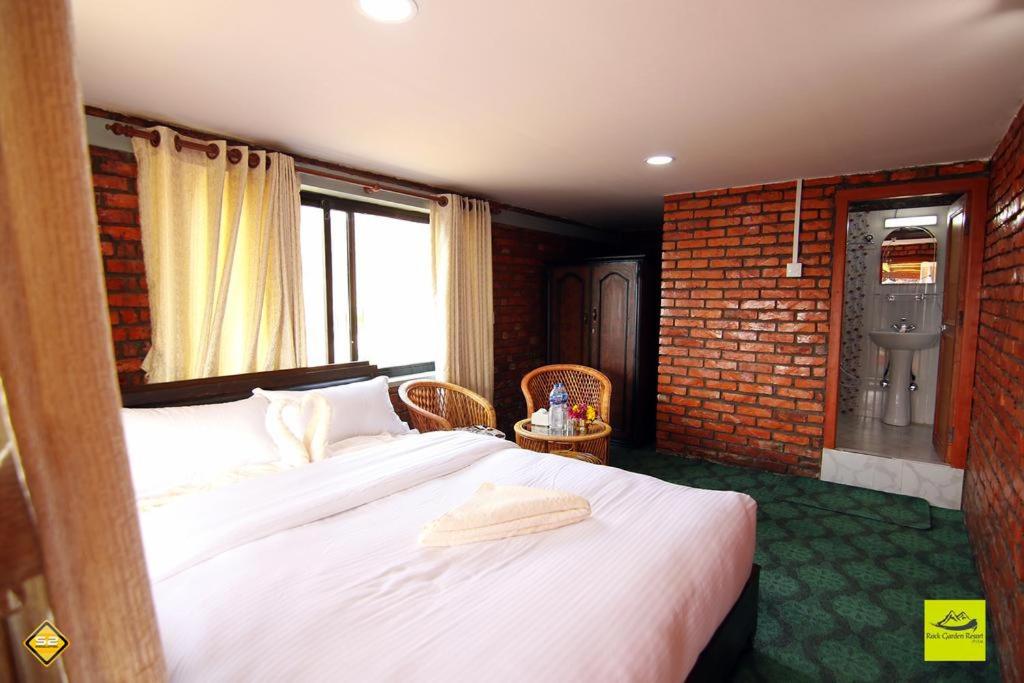 a bedroom with a large bed and a brick wall at Rock Garden Resort in Pokhara