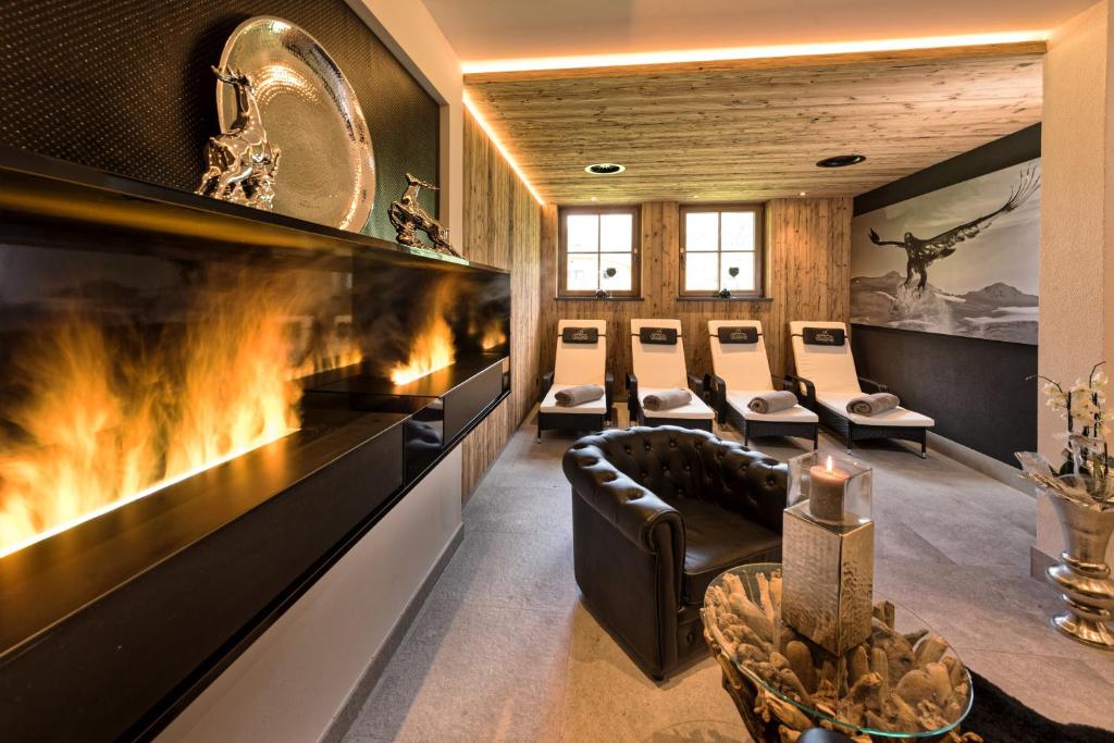 a waiting room with a large fireplace and leather chairs at Hotel Möderle in Sankt Leonhard im Pitztal