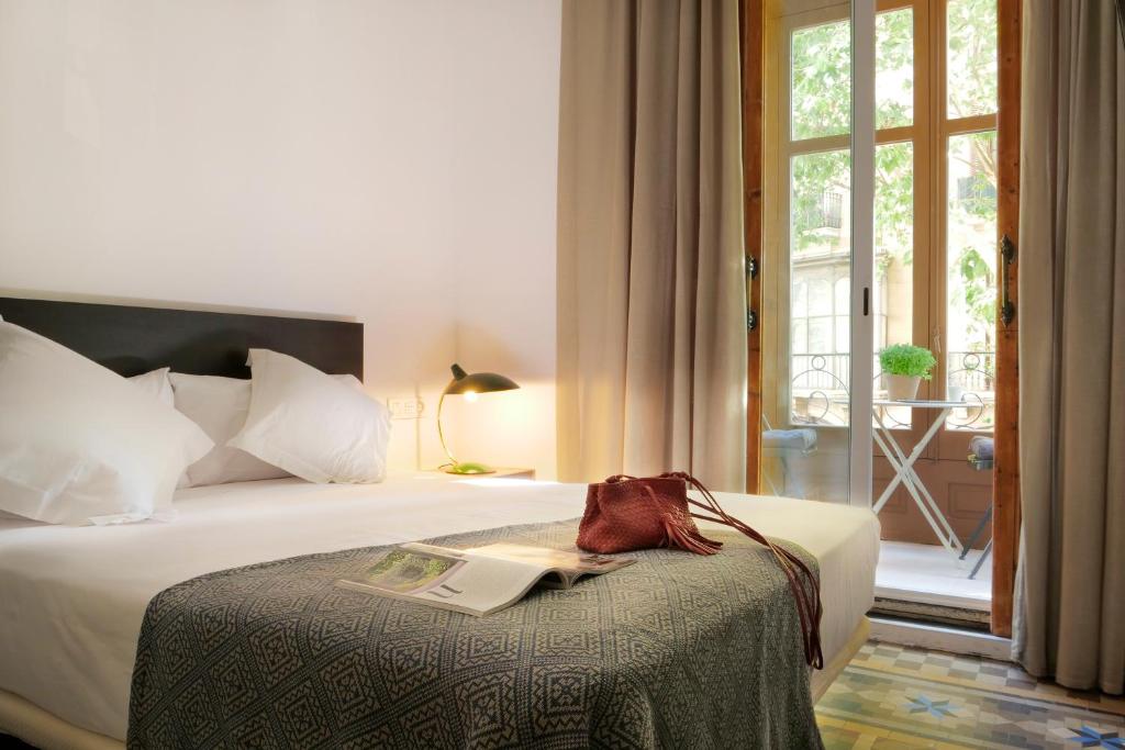 una habitación de hotel con una cama con un libro encima en Som Nit Triomf, en Barcelona