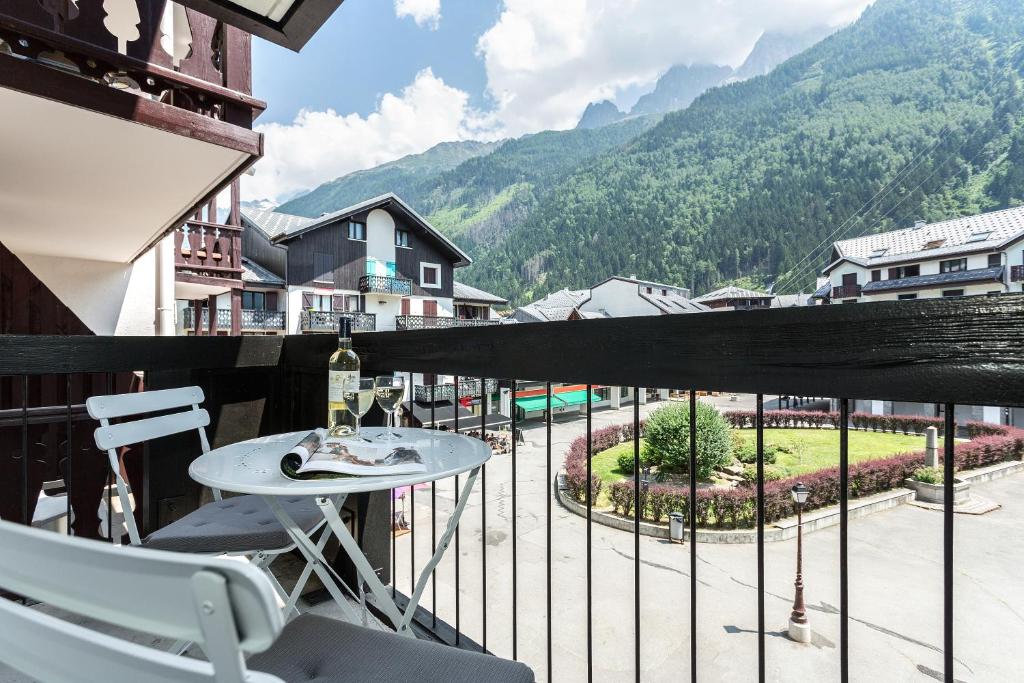 d'un balcon avec une table, des chaises et des montagnes. dans l'établissement Apartment Balme 2 - Central Chamonix Haven and Mont Blanc View, à Chamonix-Mont-Blanc